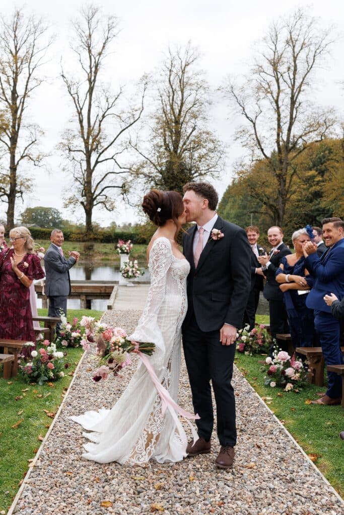 Bride and groom kiss on jetty after ceremony